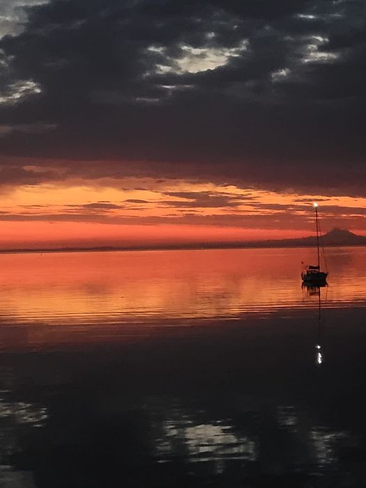Sunrise in Port Angeles, with orange sky and reflection in the water with boat in the foreground