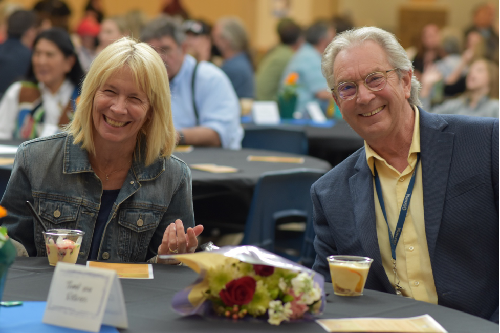 Former Executive Secondary of Education Mick Hart and his wife smile at a table at the 2022 Ice Cream Social where Mick was honored as a retiree